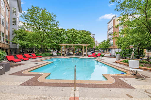 A swimming pool surrounded by trees and chairs.