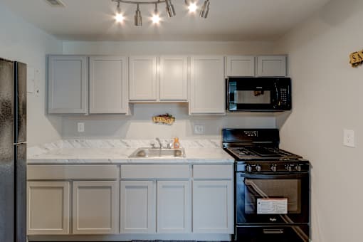 A kitchen with white cabinets and a black stove.