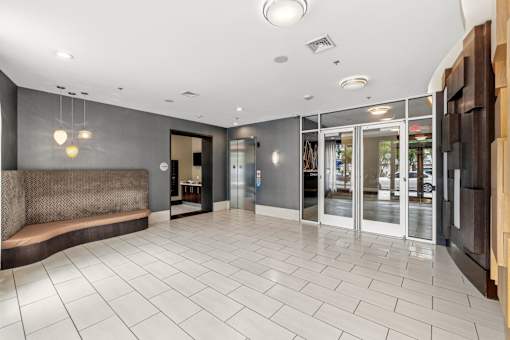 A spacious lobby with a bench and glass doors.
