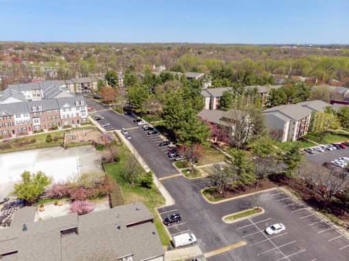 A parking lot is surrounded by buildings and trees.