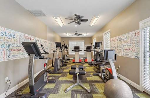 A gym with a variety of equipment including treadmills, exercise bikes, and weights.