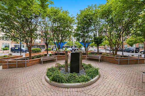 A park with a fountain surrounded by benches and trees.