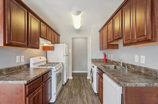 A kitchen with white appliances and brown cabinets.