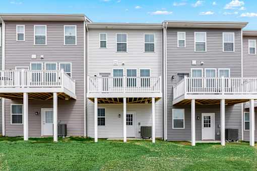 Three identical houses with balconies are lined up in a row.