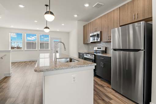A modern kitchen with a stainless steel refrigerator and wooden cabinets.