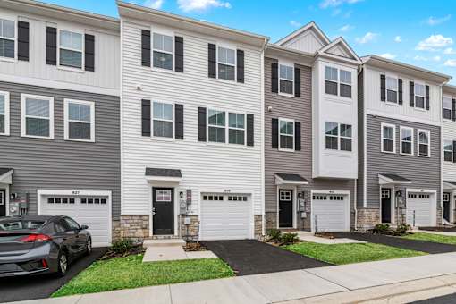 A row of townhouses with garages and a car parked in front.