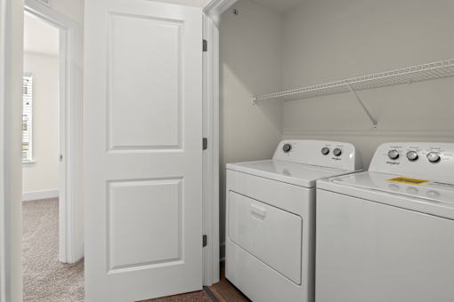 A white door is open to a laundry room with two washing machines.