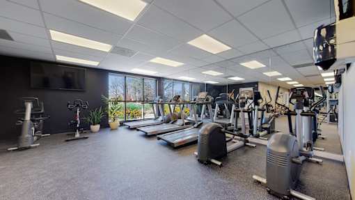 A gym with a variety of equipment including treadmills, weights, and exercise machines.