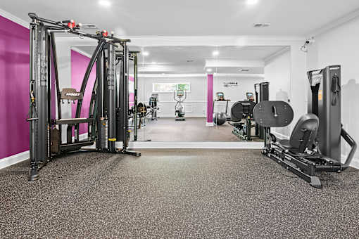A gym with a pink wall and a variety of exercise equipment.