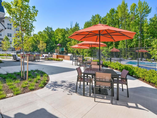 a patio with tables and umbrellas next to a swimming pool