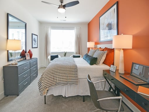 a bedroom with a bed and a desk with a laptop