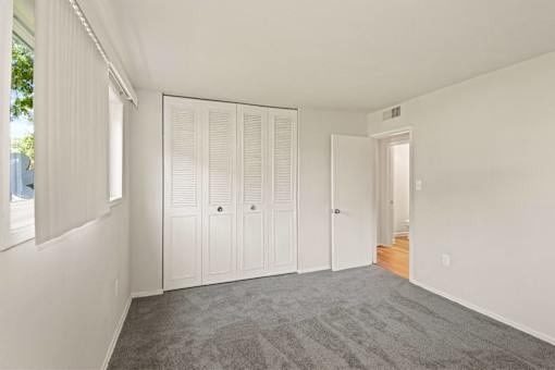 a bedroom with a carpeted floor and white closet doors