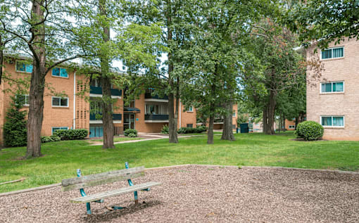 a park with a bench in front of an apartment building