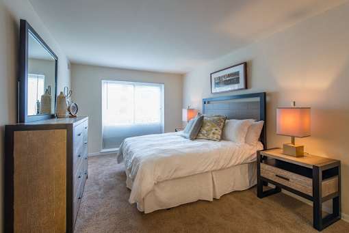 A bedroom with a bed, nightstand, and a dresser.
