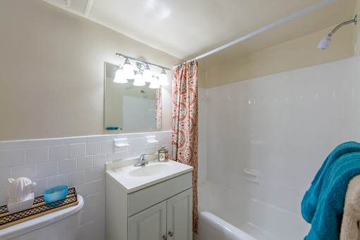 A white sink in a bathroom with a blue towel hanging on the tub.