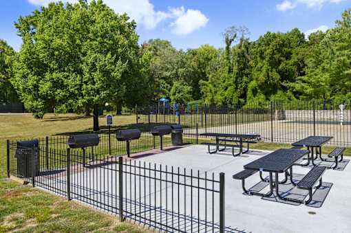 A black iron fence surrounds a picnic area.