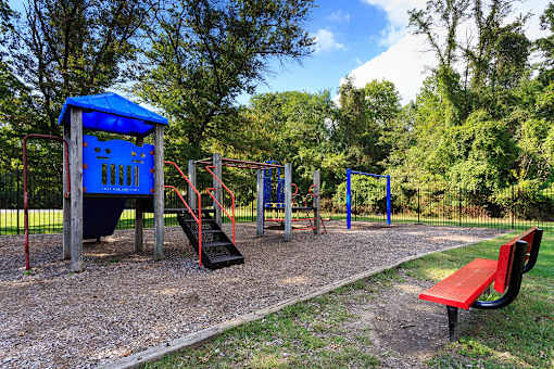 A playground with a blue shelter, red slide, and a red bench.