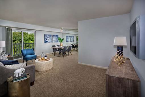 A living room with a grey couch, a blue chair, a wooden table, and a television.
