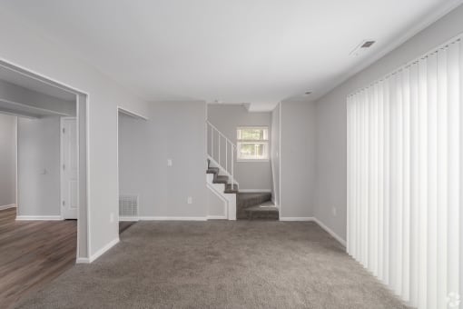 a living room with a carpeted floor and a staircase