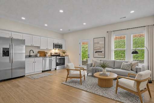 A modern kitchen with a refrigerator, cabinets, and a dining table.