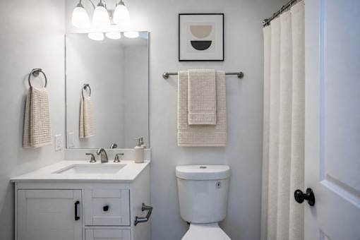 A white bathroom with a toilet, sink, and shower curtain.