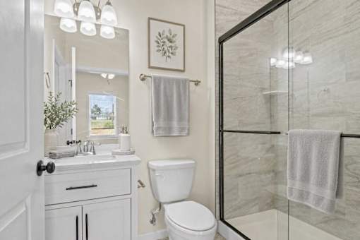 A white bathroom with a toilet, sink, and mirror.