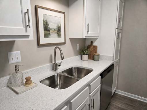A kitchen with a white countertop and a painting hanging above the sink.