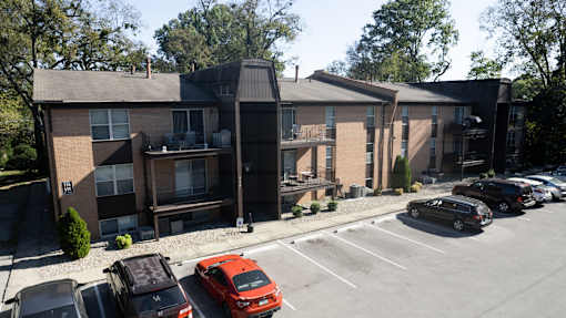 a parking lot in front of a brick apartment building with cars parked