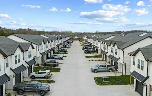 A row of houses with cars parked in front.