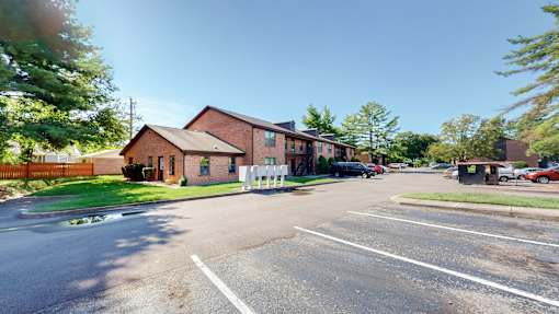 an empty parking lot in front of a brick house