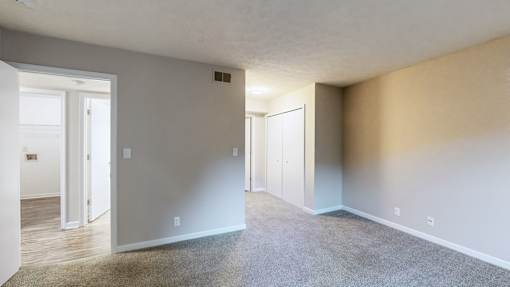 A room with a carpeted floor and a door on the left side.