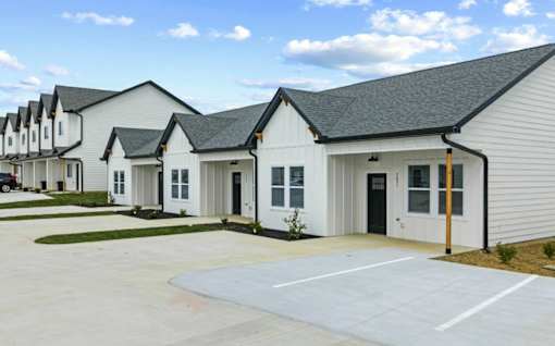 A row of white houses with black roofs and a clear blue sky.