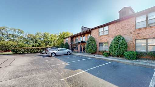 an empty parking lot in front of a brick apartment building
