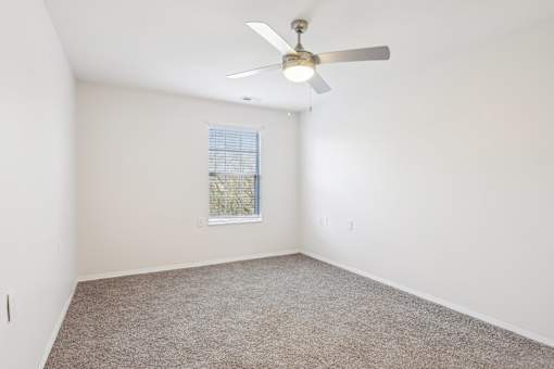 A room with a ceiling fan and carpeted floor.