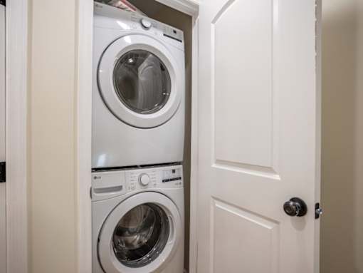 A white door is open to a small laundry room with a washer and dryer.