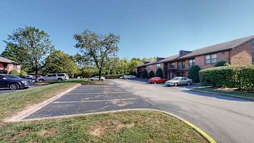 an empty parking lot in front of a brick apartment building