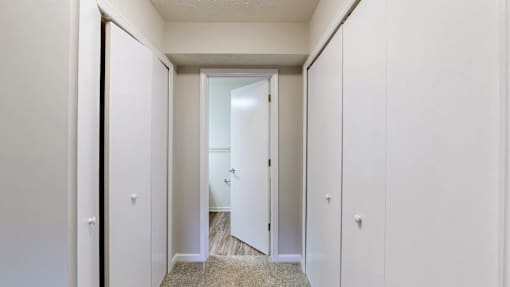 A hallway with white walls and a carpeted floor.
