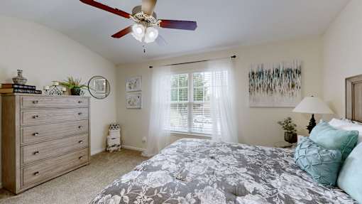 A bedroom with a large bed and a ceiling fan.