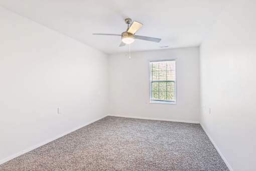 A room with a ceiling fan and a window with blinds.