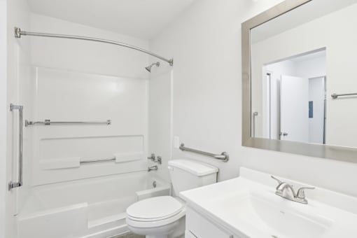 A white bathroom with a toilet, sink, and shower.