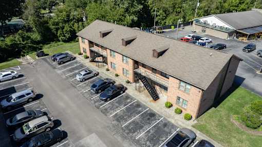 an aerial view of a brick building with cars parked in a parking lot