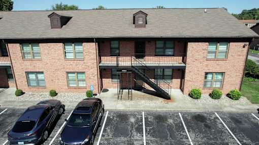 an aerial view of a brick apartment building with three cars parked in front