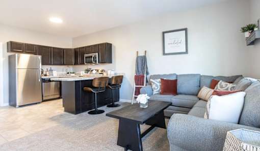 A modern kitchen with a grey couch and a black table.