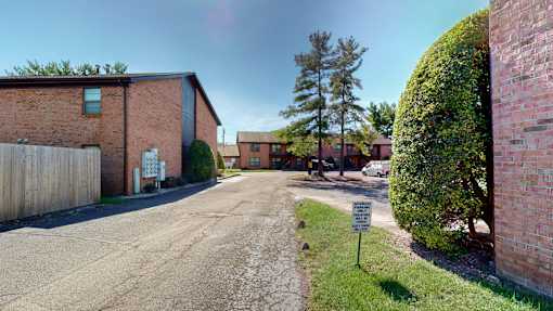 a street in front of a brick building with a sign in the grass