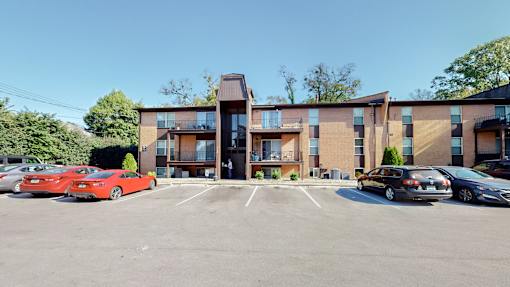 a parking lot in front of a brick apartment building with cars parked