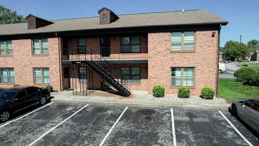 a brick apartment building with a balcony and cars in a parking lot