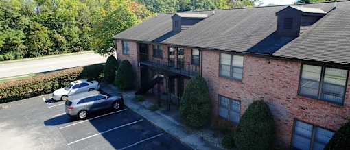 an aerial view of a brick house with cars parked in a parking lot