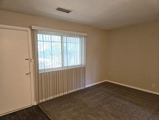 an empty living room with a window and a door
