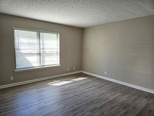 an empty living room with wood floors and a window