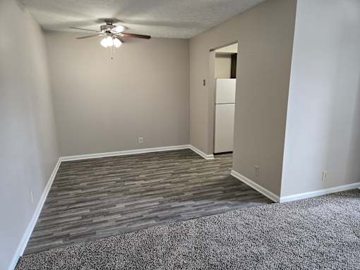 A room with a ceiling fan and a door leading to another room.